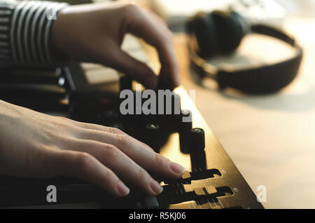 A woman in a shirt sets up a synthesizer, two hands in the frame Stock Photo