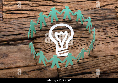 Green Paper Business Team Surrounding Light Bulb On Table Stock Photo