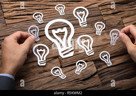 Businessman Arranging Paper Light Bulbs Stock Photo