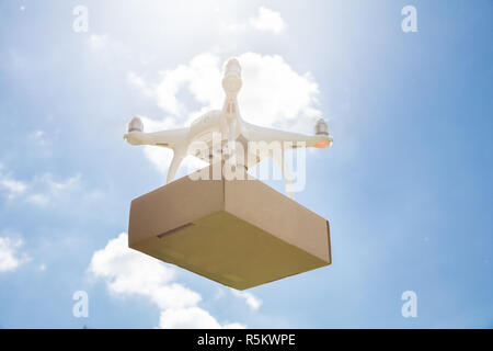 Drone delivering parcel against sky on sunny day Stock Photo
