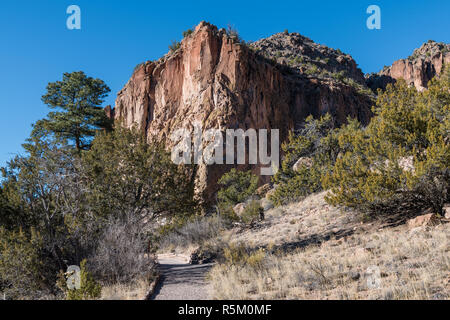 Pathway leading to a colorful high red rock peak in Bandelier National Monument near Santa Fe, New Mexico Stock Photo