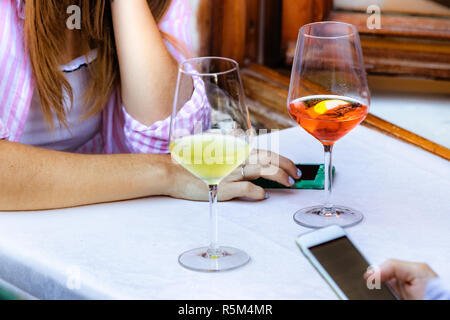 Young woman using her mobile having a drink in a bar outdoors, Italy. Stock Photo