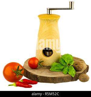 nutmeg mill on wooden board with basil leaves,tomatoes,peppers and nutmegs Stock Photo