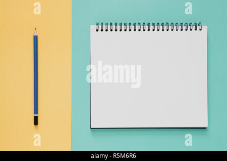 Office workplace minimal concept. Blank notebook, pencil on yellow and green turquoise background. Stock Photo