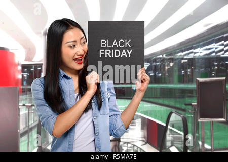 Young asian woman holding sign board with Black Friday text Stock Photo