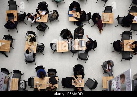 June 13, 2018, Aerial view of a group of people sitting at tables in a cafe, talking, drinking coffee, using their cell phones and laptop computers. Stock Photo