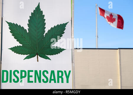 A cannabis dispensary sign with a large marijuana leaf on it and a Canadian flag in the background. Stock Photo