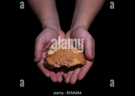 Poverty concept. Hands holding bread isolated on balck background. Stock Photo