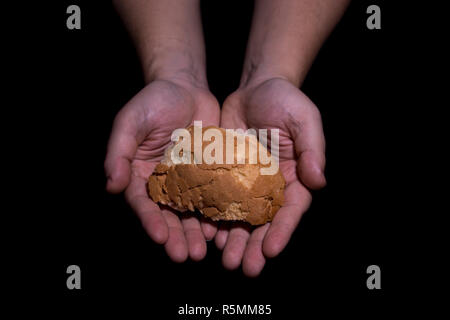 Poverty concept. Hands holding bread isolated on balck background. Stock Photo