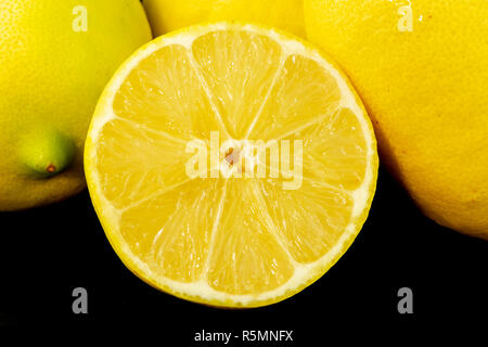 Fresh sliced and whole lemons with isolated black background Stock Photo