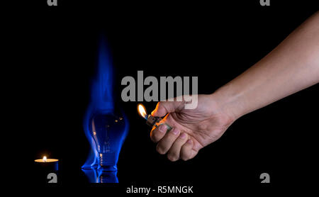 Hand lighting a lightbulb isolated on black background. Wrong usage concept. Stock Photo