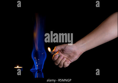 Hand lighting a lightbulb isolated on black background. Wrong usage concept. Stock Photo
