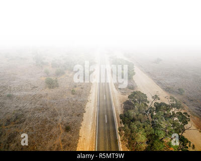 Aerial view of straight rural road leading into white fog Stock Photo