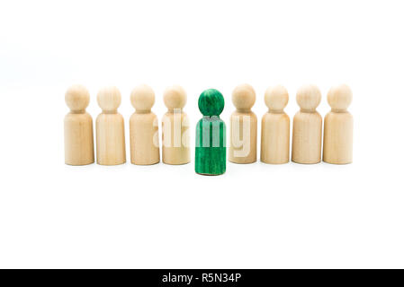 Wooden figures in line as business team, with one green figure standing out from the crowd, isolated on white background. Conceptual image of being di Stock Photo