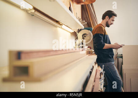 Craftsman using cell phone in his workshop Stock Photo