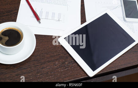 Workplace of businessman with digital tablet, smartphone, Cup of coffee and charts. The concept of a startup business Stock Photo