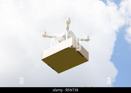 Drone delivering parcel against sky on sunny day Stock Photo