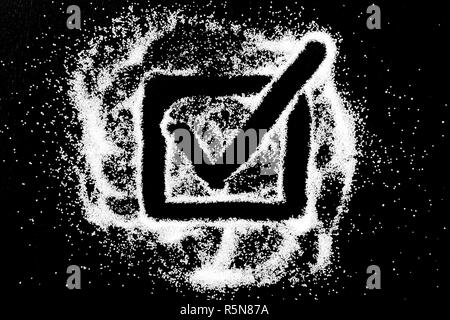 Checking mark symbol with long tail in checkbox drawing by finger on white snow salt powder spot cloud in center on black background. Tick concept with place for text. Copy space. Stock Photo