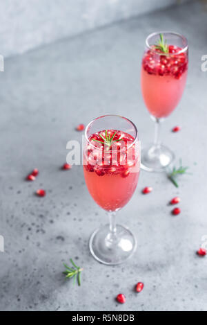 Pomegranate Champagne Mimosa Cocktail (Mocktail) with rosemary on concrete background, copy space. Mimosa Drink for Valentine Day or other holidays. Stock Photo