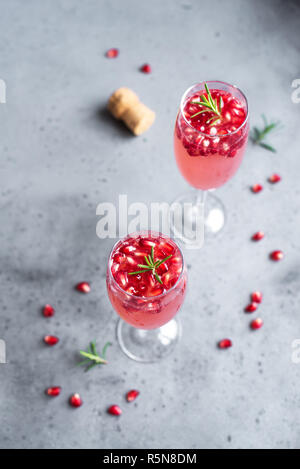 Pomegranate Champagne Mimosa Cocktail (Mocktail) with rosemary on concrete background, copy space. Mimosa Drink for Valentine Day or other holidays. Stock Photo