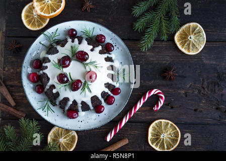 Christmas Pudding, Fruit Cake decorated with icing and cranberries on rustic wooden table,  top view. Homemade traditional christmas dessert - Christm Stock Photo