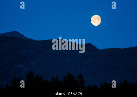 Twilight in mountains with full moon Stock Photo