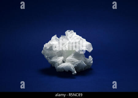 Crumpled white paper texture on dark blue background under dramatic moody lighting Stock Photo