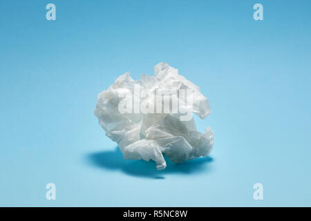 Crumpled white paper texture on light blue background under dramatic moody lighting Stock Photo