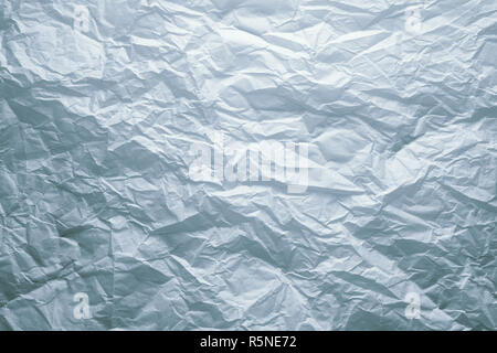 Crumpled white paper sheet background under dramatic dark moody lighting Stock Photo