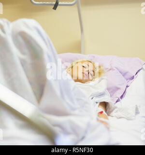 Bedridden female patient recovering after surgery in hospital care. Stock Photo