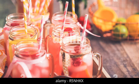 Raspberry lemonade garnished with fresh lemon and raspberries in drinking mason jars. Stock Photo