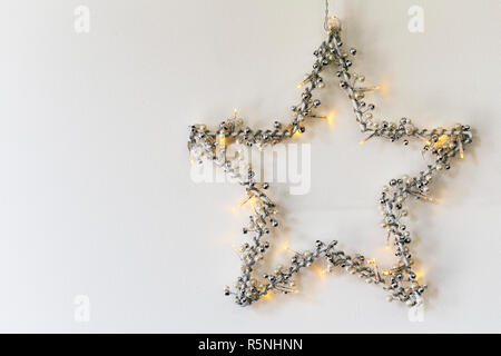 Christmas star with lights hanging on white wall Stock Photo