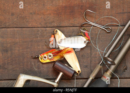 Closeup of spinning rod and other fishing tacle lying on wooden background Stock Photo