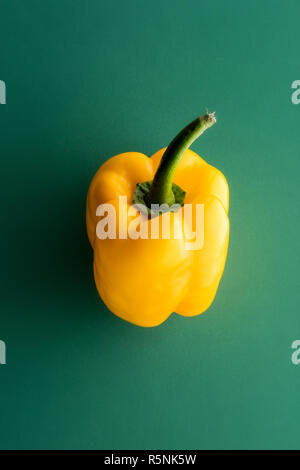 One whole yellow sweet pepper on green background, viewed from above in close-up Stock Photo