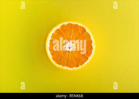 One half of sliced ripe orange viewed from above in center isolated on yellow background Stock Photo