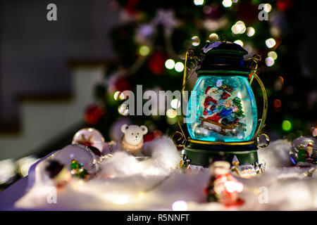 Christmas decoration, snow dome, globe with table decoration, Santaclaus on sleigh with child in winter scene, christmas tree with lights in Stock Photo