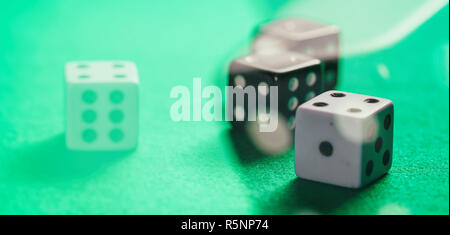 Casino, gambling concept. White and black dice on green felt abstract background, banner Stock Photo