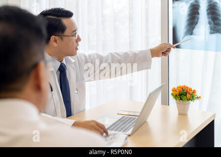 Professional doctor explain about x-ray result to patient in medical office hospital - Selective Focus at doctor’s hand Stock Photo
