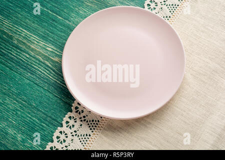 Empty pink plate on tablecloth on wooden table. Top view. Stock Photo