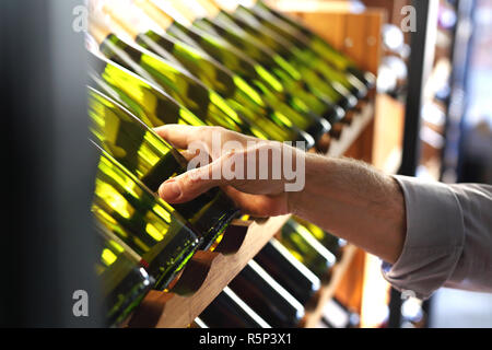 Bottles of wine in the wine cellar. Man chooses wine. Stock Photo