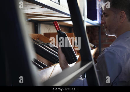 Bottles of wine in the wine cellar. Man chooses wine. Stock Photo