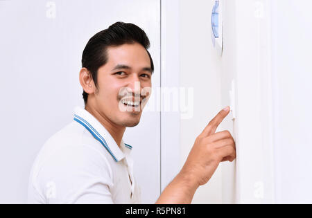 Handsome asian man turning off the light with wall switch Stock Photo