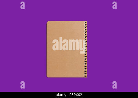 beige spiral notebook on purple background Stock Photo
