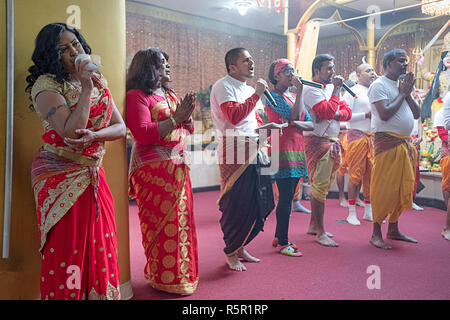 Worshippers praying and chanting as one woman blows into a conch shell. In Queens, New York City. Stock Photo