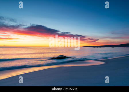 Sunrise at Bay Of Fires, Tasmania, Australia. Red lichen and a dramatic sunrise with white sand. Stock Photo