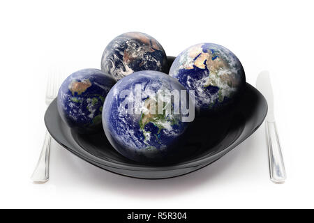 How many Earths do we need to satisfy our hunger? Concept about the overuse of our Planet Earth displaying four globes on plate. Stock Photo