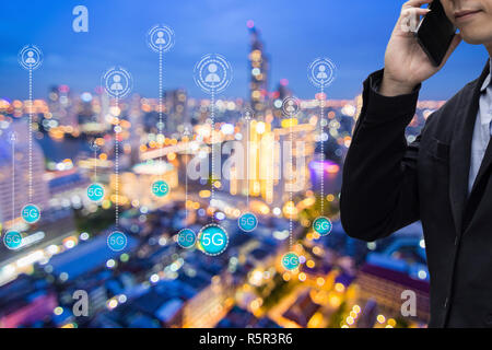 businessman call phone with connection people and 5G icon on night city background, technology and internet concept Stock Photo