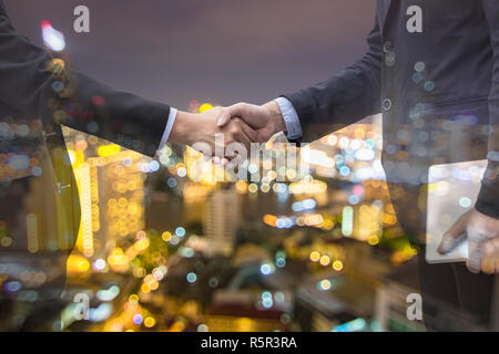 double exposure businessman shake hand and night city, handshake of successful business concept Stock Photo