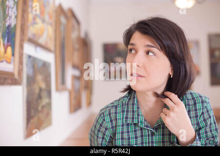 A young beautiful woman looking at painting in an art gallery. Stock Photo