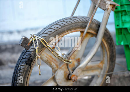 Close-up photography. An old motorcycle front wheel is locked in the iron chain. Stock Photo